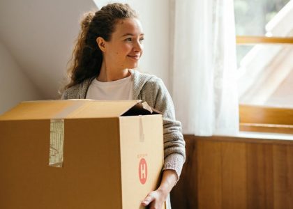 Junge Frau trägt einen Umzugskarton